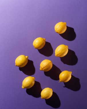 Mor arkaplanda dramatik gölgeler olan limonlar