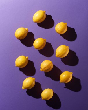 Mor arkaplanda dramatik gölgeler olan limonlar