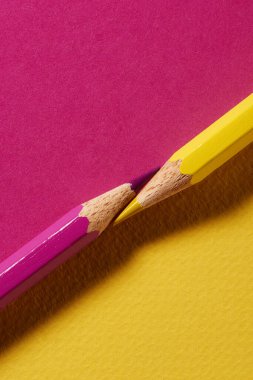 Koordineli kağıt arkaplanda pembe ve sarı renkli kalemlerin makro görüntüsü