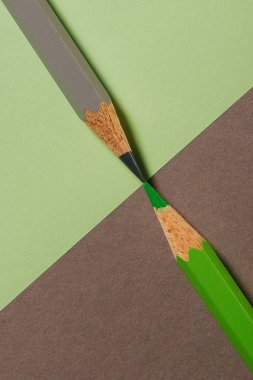 Koordineli kağıt arka planında yeşil ve gri renkli kalemlerin makro görüntüsü
