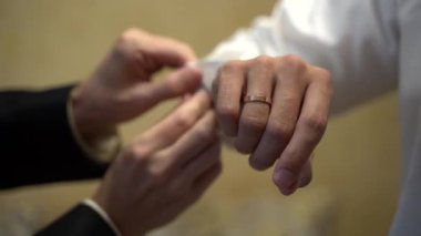 Bir adam diğerinin beyaz gömlek giymesine yardım eder..