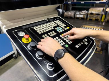 Bir adam yeni beş eksenli CNC değirmen makinesinin işlevselliğini test etmek için yeni bir kod yazar.