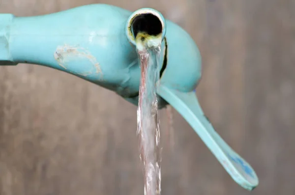 Bulanık bir mutfakta açık mavi plastik bir musluğun ayrıntıları