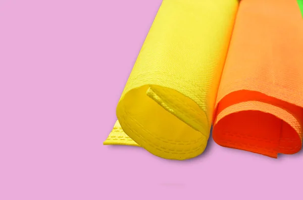 roll of yellow and orange non-woven fabric on a pink background and copy space for text