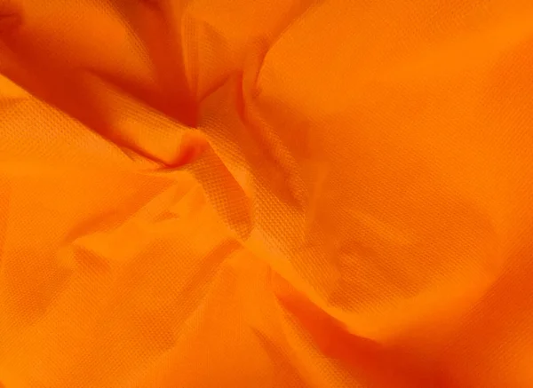 coarse porous orange non-woven fabric surface background. polypropylene fabric texture