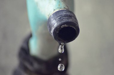 Mavi plastik bir musluktan su damlacıkları. Kırık ve yosunlu bir musluktan düşmek 