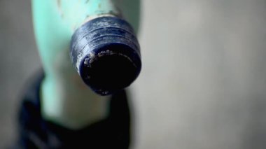 Mavi plastik bir musluktan temiz su damlacıkları. Kırık ve yosunlu bir musluktan yıkık dökük bir binanın arka planına düşmek.