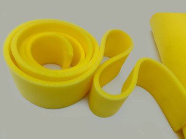 Gri arkaplanda daire şeklinde sarı köpük bir sünger parçası. İnce madde sarmal bir şekle bürünmüş.