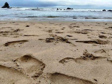 Kumsalın kenarında insan ayak izleri var. Beyaz kum. Sakin dalgalarla deniz manzarası
