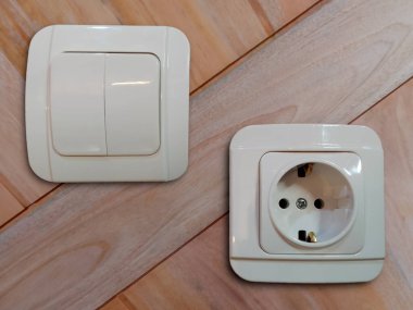 Tahta duvarın yüzeyine iki beyaz priz ve elektrik prizi bağlanmış..