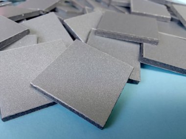 Mavi yüzeyde alüminyum metal yığını. Küçük kare parçalar. Kalın malzeme. Alüminyum bileşik panel atığı