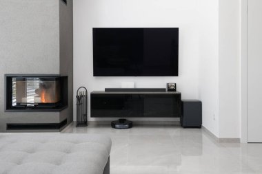 Modern apartmandaki modern oturma odasının ayrıntıları. Televizyon ve şömineli duvar.