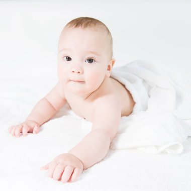 Happy little baby in white towels after bath