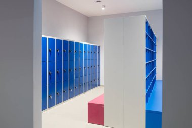 Kilitli bir duvarda mavi dolaplar boş raflar ve banklarla dolu bir dolap.