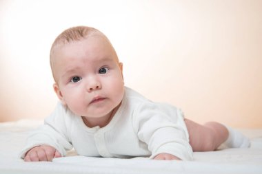 meraklı küçük bebek battaniyenin üzerinde yatıyor, turuncu arka plan