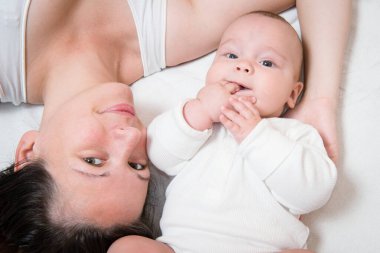 Mutlu anne ve tatlı bebeği yatakta yatıyor.