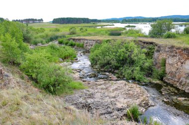 Sakin bir nehrin üzerindeki kireçtaşı kayalıkları. Yaz manzarası.