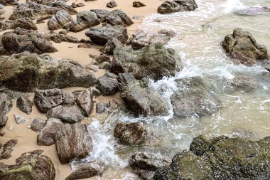 Sörf suyunda sahilde taşlar, tropikal deniz.