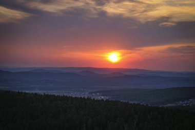 Dağların ve kırsal köyün üzerinde renkli günbatımı.