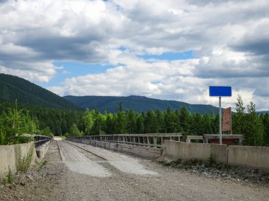 Dağlardaki bir nehrin üzerinde, seyrek nüfuslu bir bölgede eski bir ahşap köprü..