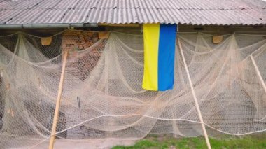 Ukrainian flag and fishing net near an old barn