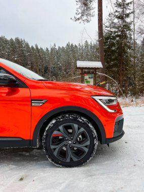 Riga, Letonya - 25 Ocak 2023: Renault Arkana RS-line Valencia Orange kışın küçük çaplı bir SUV E-teknoloji hibrit araba. Fransız otomobil üreticisi.