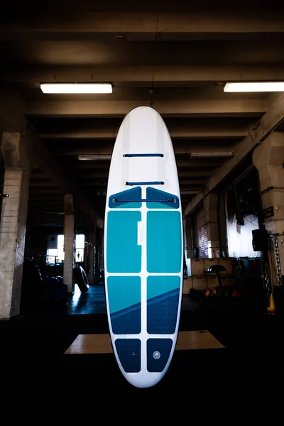 stock image Blue inflatable stand-up paddle board SUP by the wall. Surfing and sup boarding equipment close up.