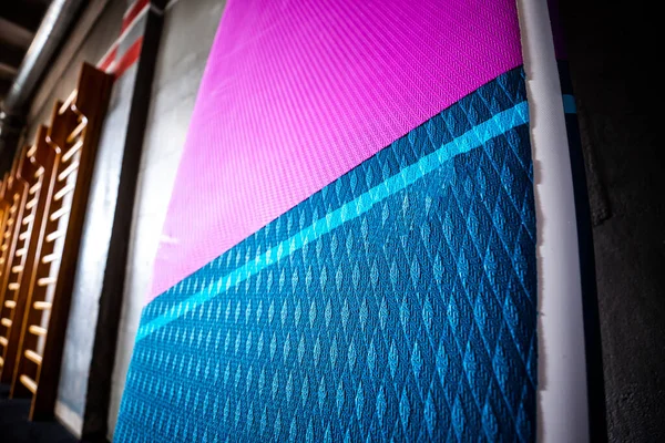 stock image Blue and pink stand-up paddle boards SUP by the wall. Surfing and sup boarding equipment close up.