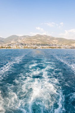 Sahildeki bir yatın manzarası denizin ve sahilin güzelliğini ve huzurunu gözler önüne seriyor.