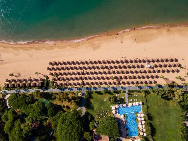 Plaj sandalyeleri ve palmiye ağaçları olan bir sahil manzarası. Lüks bir yaz adası tatili kavramının somutlaştırılmış hali. Rahatlama ve huzurlu bir kaçış.