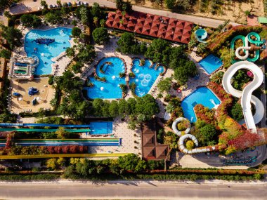 Lüks bir sahil otelinde geniş havuzlu ve slaytlı bir su parkı manzarası. Eğlenceli ve rahatlatıcı bir tatil için mükemmel..