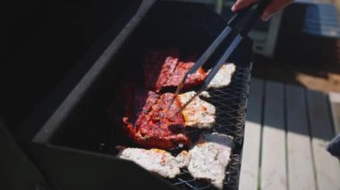 Yanan ateşte çiğ et kızartmak, pişmiş bifteği ızgarada pişirmek için maşa kullanmak. Barbekü dumanı ve alevler, ateşte ızgara et. Barbekü ve piknik konsepti