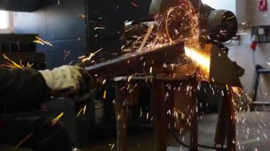 Kesme makinesiyle bir metali keserken, dışarıdaki yangın kıvılcımları sıçrar..