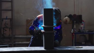 Metal fabrikasında kaynakçılık. Miğferli bir kaynakçı kaynak masasına metal bir parça yapıştırır.