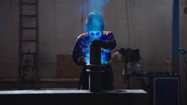 Metal fabrikasında kaynakçılık. Miğferli bir kaynakçı kaynak masasına metal bir parça yapıştırır.