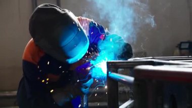 Metal fabrikasında kaynakçılık. Miğferli bir kaynakçı kaynak masasına metal bir parça yapıştırır.