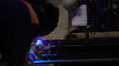 Metal fabrikasında kaynakçılık. Miğferli bir kaynakçı kaynak masasına metal bir parça yapıştırır.