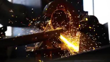 Kesme makinesiyle bir metali keserken, dışarıdaki yangın kıvılcımları sıçrar..