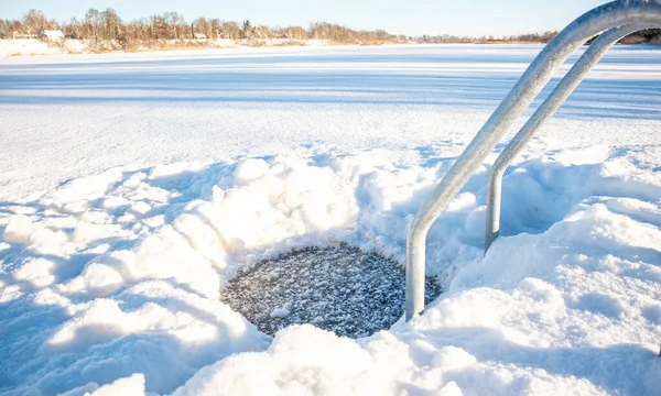 Buzlu bir merdivenle parlak bir kış günü. Karla kaplı bir gölde, buzla kaplı bir deliğe açılıyor.