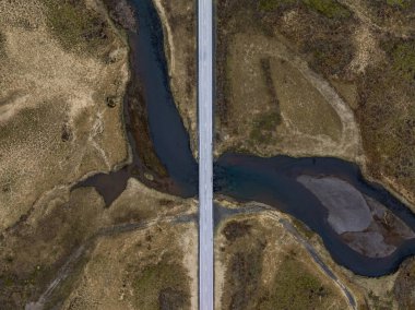 Sarmal nehirler ve geniş araziler üzerinden geçen uzun düz bir yolu olan İzlanda manzarası.