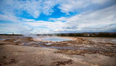 Strokkur gayzeri parlak mavi gökyüzünün altında İzlanda 'da patlıyor.