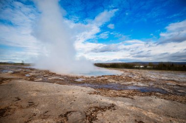 Strokkur gayzeri parlak mavi gökyüzünün altında İzlanda 'da patlıyor.