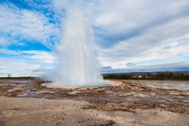 Strokkur gayzeri parlak mavi gökyüzünün altında İzlanda 'da patlıyor.