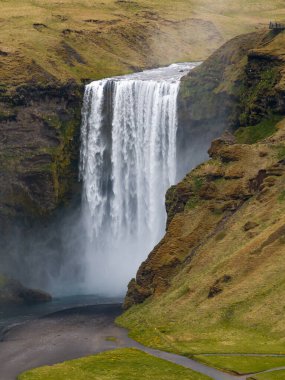 Skogafoss şelalesi, ünlü doğal bir dönüm noktası ve seyahat yeri. Yaz boyunca İzlanda 'nın etkileyici güzellikte doğası