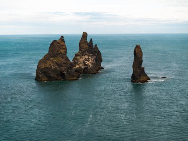 Reynisfjara 'daki kayalıkların ve deniz yığınlarının havadan görünüşü siyah kumsal, İzlanda.