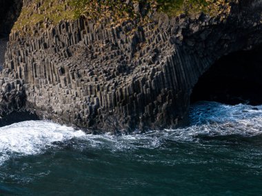Reynisfjara siyah kumsal, İzlanda 'da bazalt sütunlarının hava manzarası ve çarpışan dalgalar..