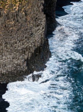 Reynisfjara siyah kumsal, İzlanda 'da bazalt sütunlarının hava manzarası ve çarpışan dalgalar..
