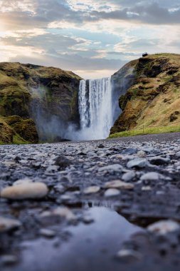 İzlanda 'daki Skogafoss şelalesinin görkemli manzarası, ünlü bir doğa ve seyahat merkezi.