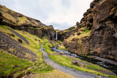 İzlanda 'daki Kvernufoss şelalesinde yemyeşil, engebeli uçurumlar, kıvrımlı bir patika ve çağlayan bir şelale bulunur.