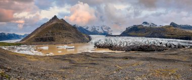 İzlanda 'da gün batımında Svinafelljokull buzulu ve buzul gölünün canlı gökyüzü manzarası nefes kesici.